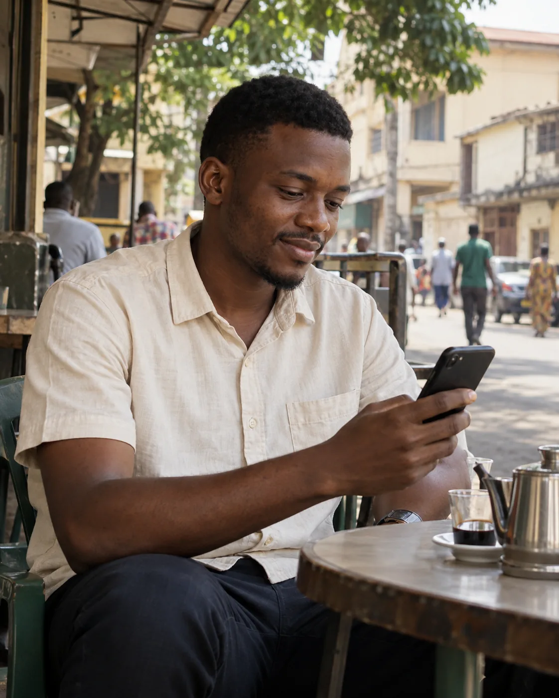 Un jeune homme consulte son téléphone à la terrasse d’un café, dans une rue de Conakry.